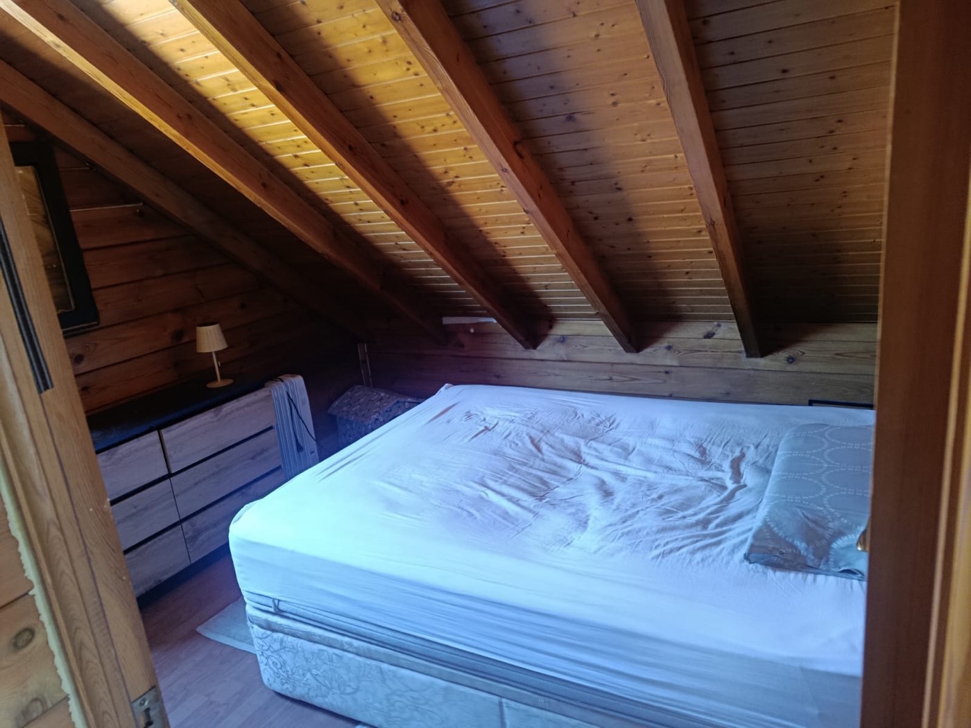 Una de las habitaciones de The Forge, cama de matrimonio bajo el techo de madera abuhardillado